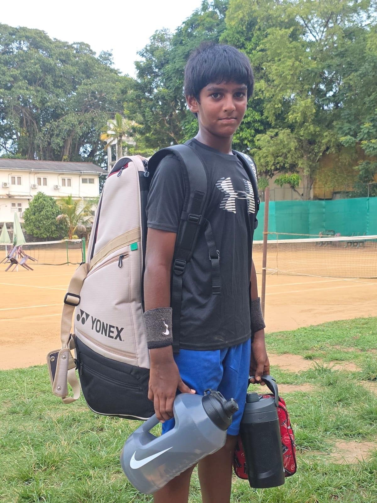 Zacharia carrying his Yonex racket bag beside the clay courts