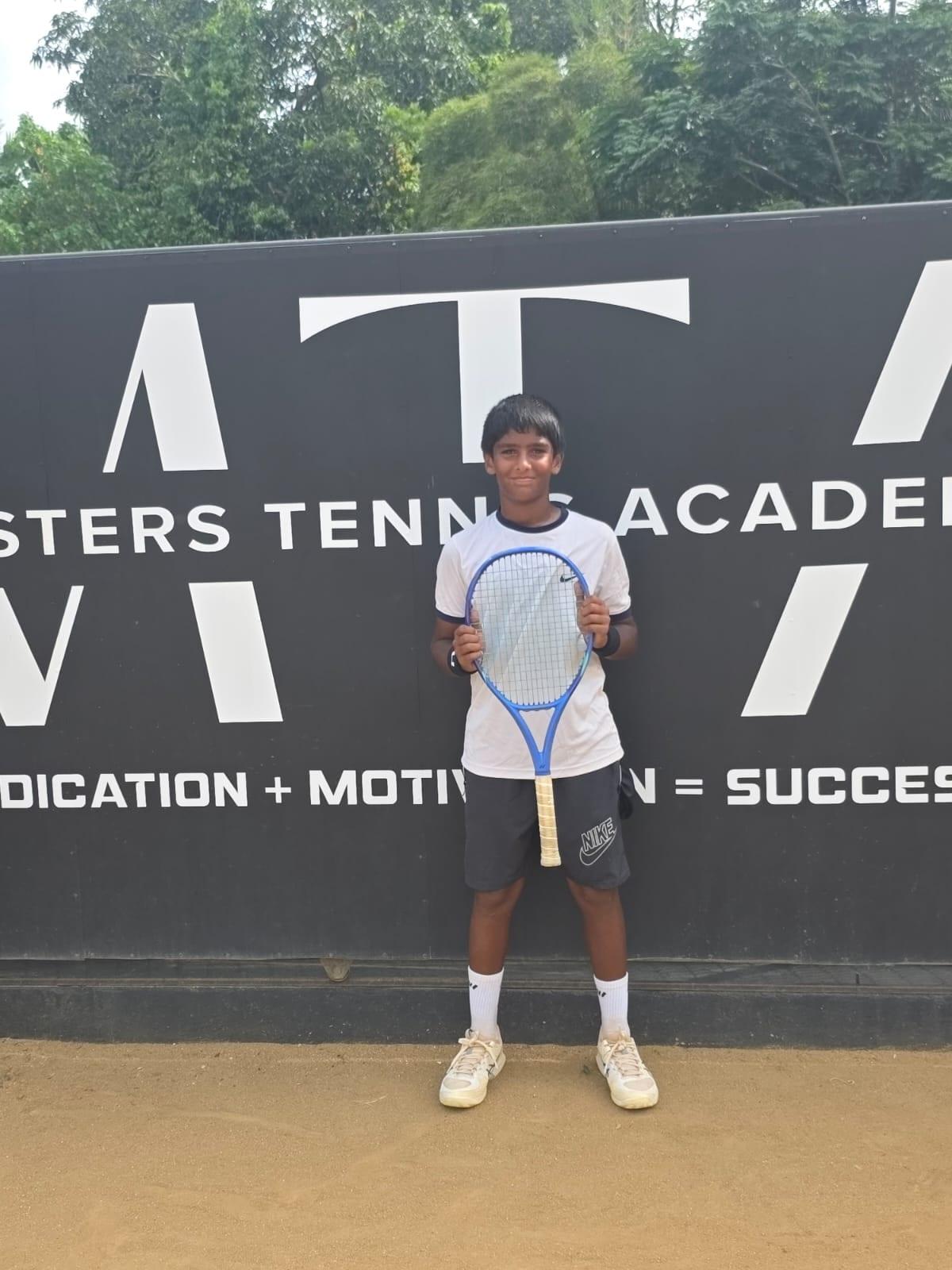Zacharia with his Yonex racket in front of the Masters Tennis Academy wall